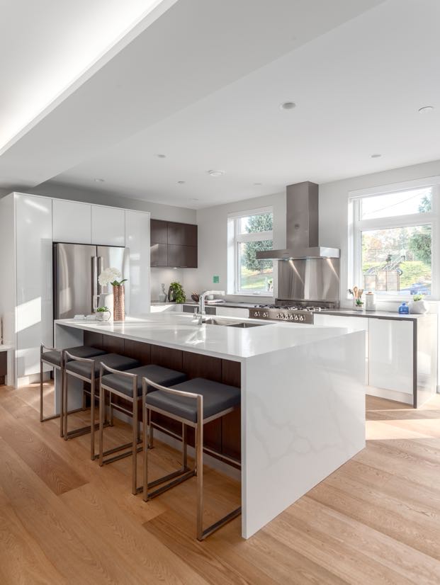 Interior image from the dining overlooking kitchen, timeless design with white millwork, marble waterfall kitchen island and two kitchen windows that provides lots of natural light.