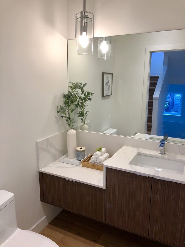 Interior image of a white bathroom with the mirror looking to the staircase.