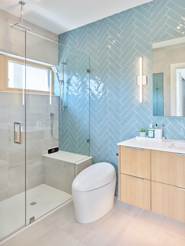 Interior image of a bathroom with the shower with serene light blue tile walls.