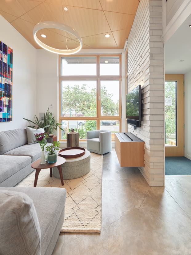 Interior image from the hallway looking to living room, featuring large triple glaze living window that gives warm and light and creates cozy atmosphere for the family.