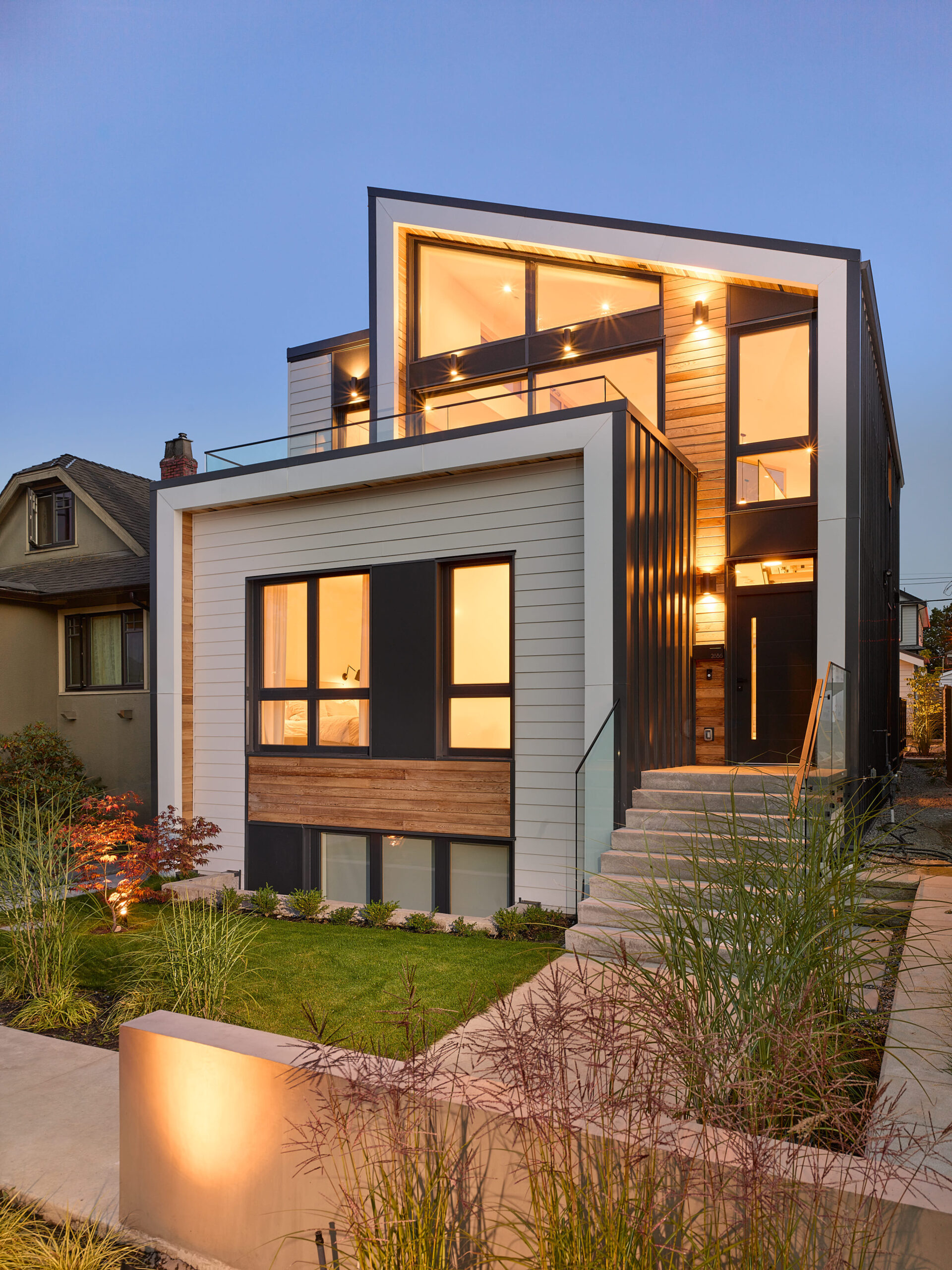 A photo from the street looking to a modern and flexible, ultra-sustainable house with secondary suite has a reverse layout to enjoy incredible views of the North Shore designed by N B A architects. Featuring a second level deck patio.