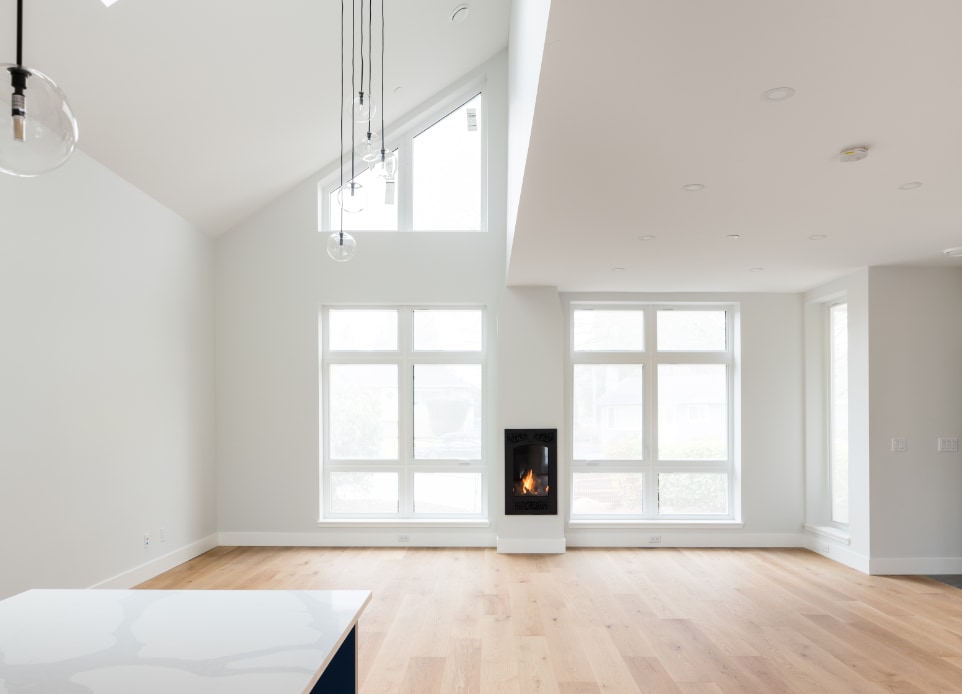 Interior image of the high ceiling living space featuring the fireplace and hardwood floors with extra big glazing that allows plenty of natural light to the space.