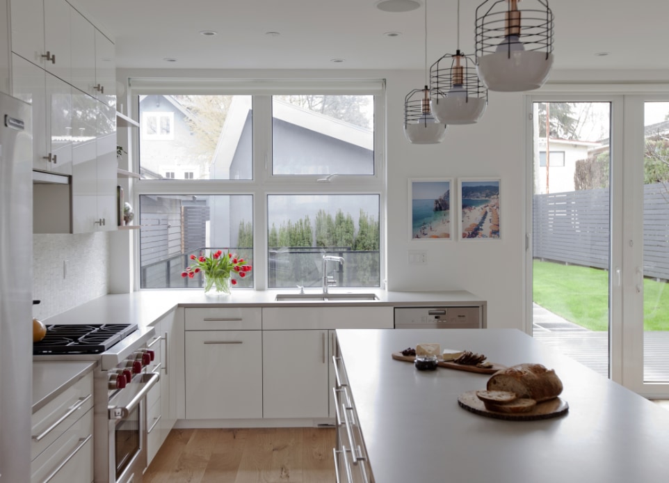 Interior image of bright kitchen featuring big window and sliding doors opening to the patio and overlooking the back yard.